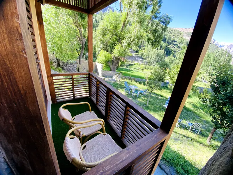 Two wicker chairs on a timber balcony overlooking the green lawns