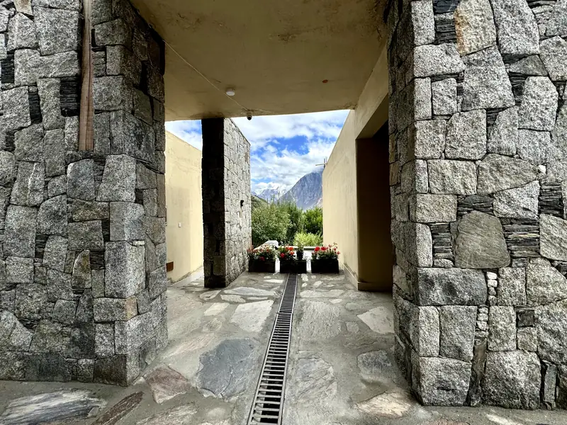 Granite walls frame a stone passage opening onto the garden and mountains